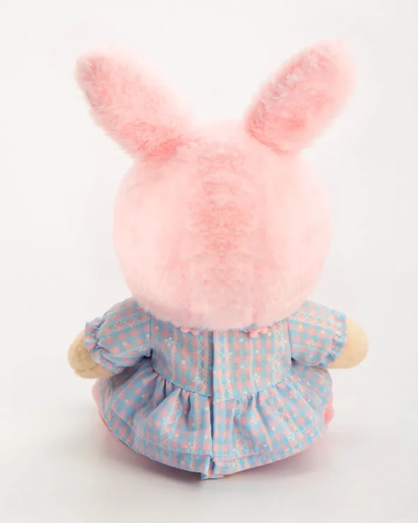 Petit ours en peluche vêtu d'une robe avec un chapeau de lapin rose assis et vue de dos