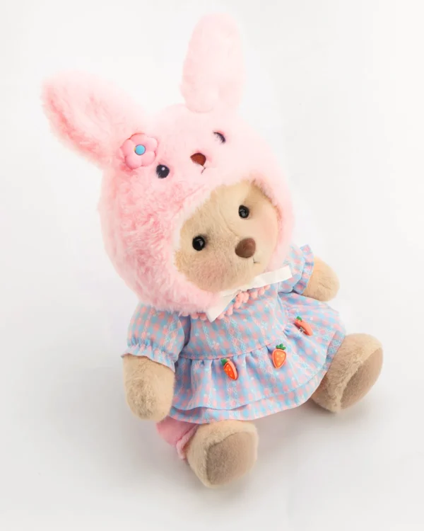 Adorable ourson en peluche avec sa robe et son chapeau en forme de lapin rose assis et vue de haut
