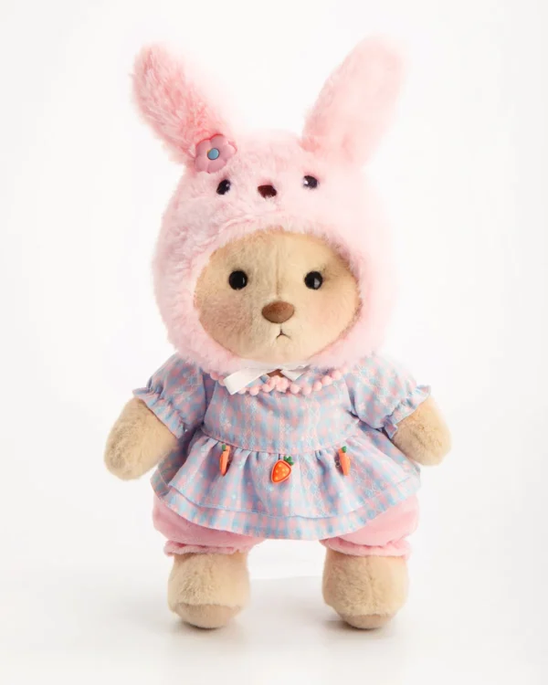 Petit nounours en peluche portant une robe et un chapeau de lapin rose debout et vue de face