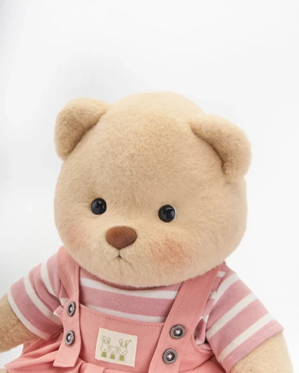 petit ours en robe salopette rose vue de près