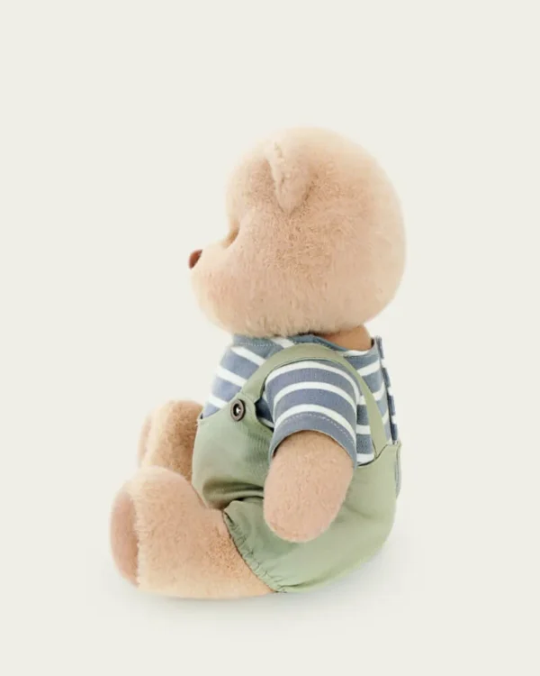 ourson en salopette verte assis avec vue de coté