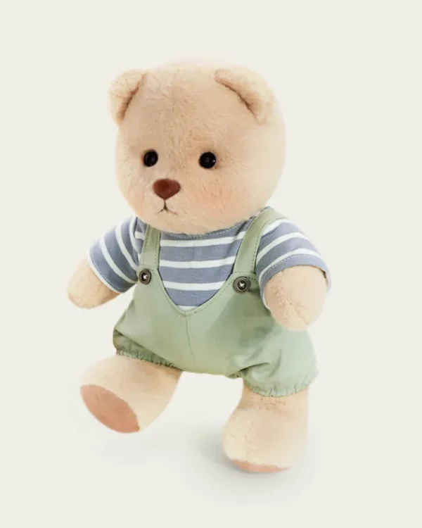 petit nounours en salopette verte debout avec une jambe en l'air