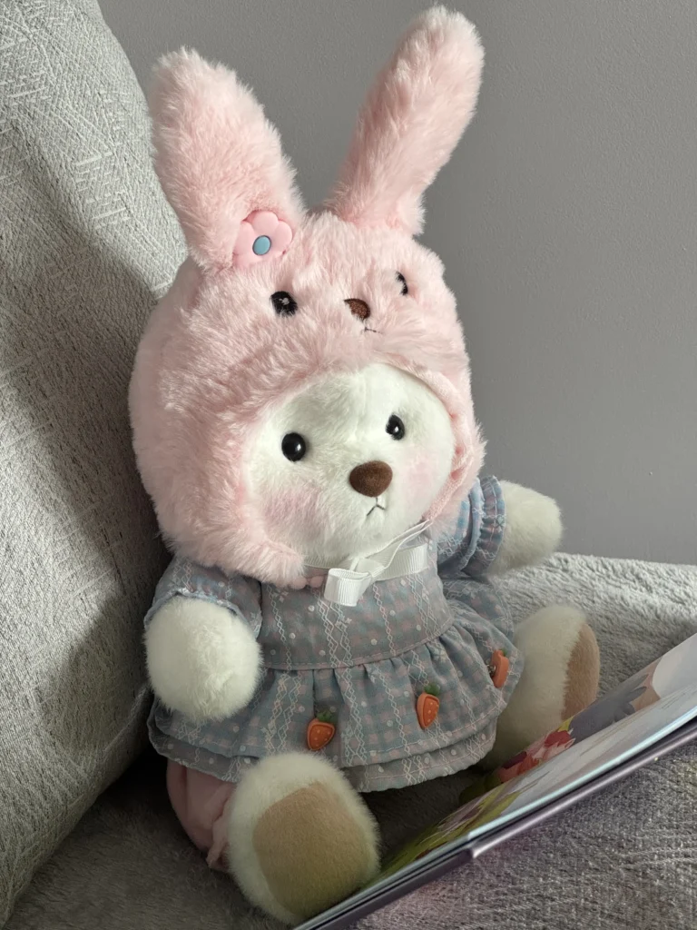 petit nounours blanc déguisé en lapin qui lit un livre
