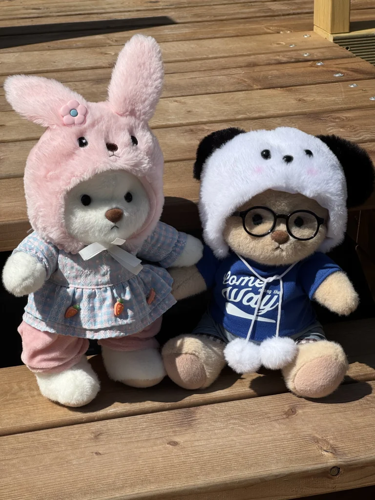 IMG_6220 petit nounours blanc habillé en lapin et petit nounours brun en pull poser sur un escalier en bois