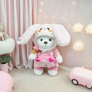 Ours en peluche Petit Nounours blanc en salopette rose et chapeau de lapin, une peluche à habiller dans une chambre d'enfant