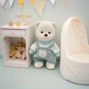 Ours en peluche Petit Nounours blanc en salopette verte et t-shirt dinosaure, une peluche à habiller dans une chambre d'enfant